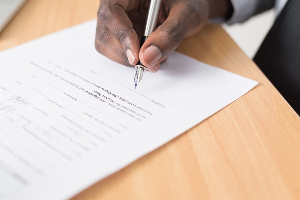 Hände eines Arbeitnehmers, der einen Änderungsvertrag vor dem Unterzeichnen durchliest
