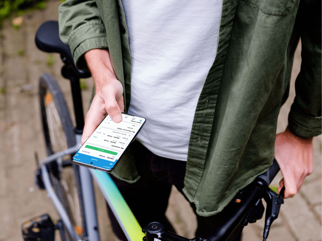 Empleado sosteniendo una bicicleta y mirando el horario en la aplicación móvil Shiftbase.