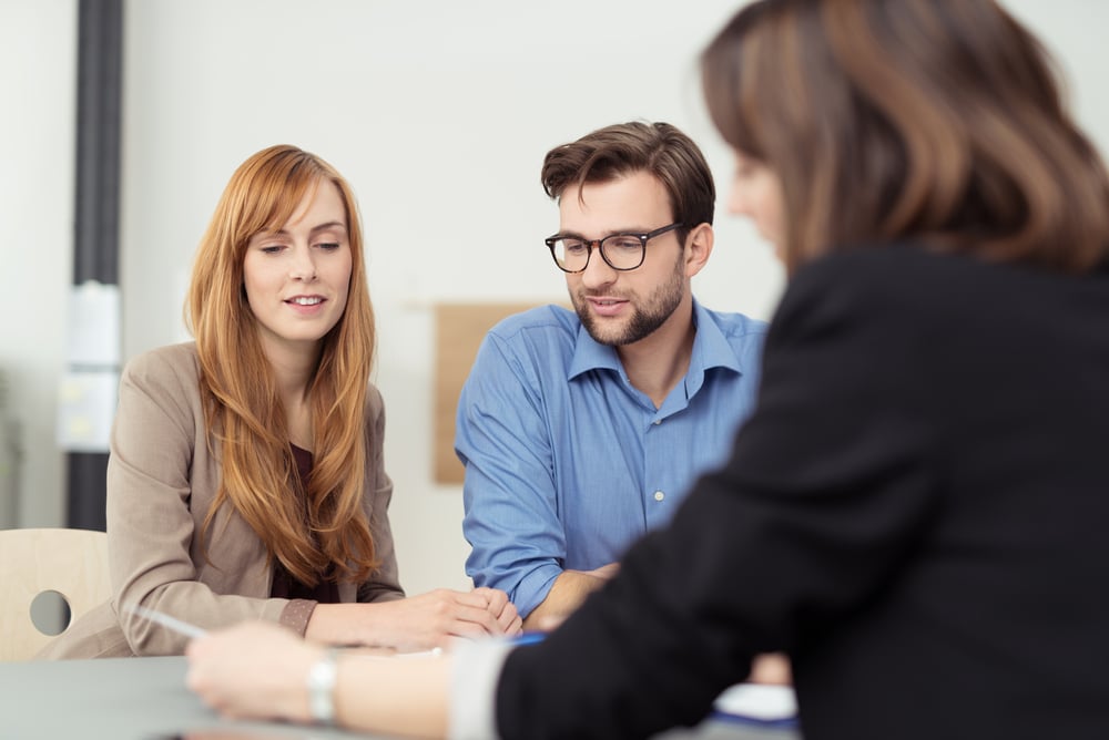 Broker presenting a document to a young couple
