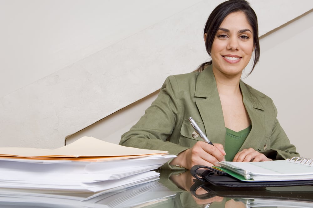 Businesswoman filing out paperwork at desk.