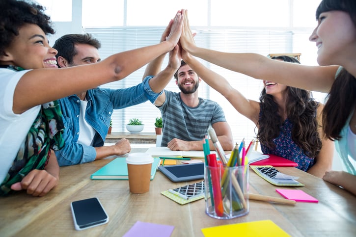 Creativo equipo de negocios en la sala de reuniones de la oficina juntando las manos para celebrar el trabajo en equipo.