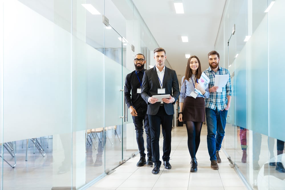 group of happy young business people walking the corridor in office together