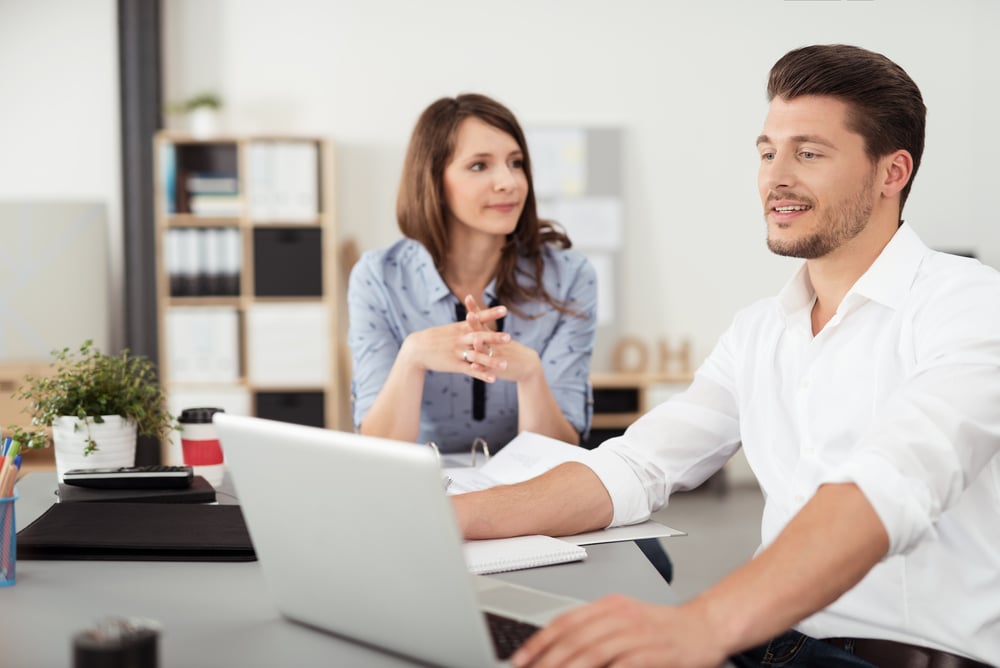 Professional Young Couple Talking About Business While Seated at the Table Inside the Office.