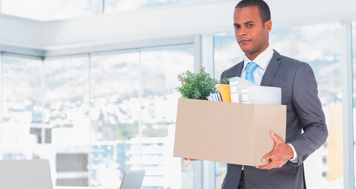 Man leaving an office and carrying moving box