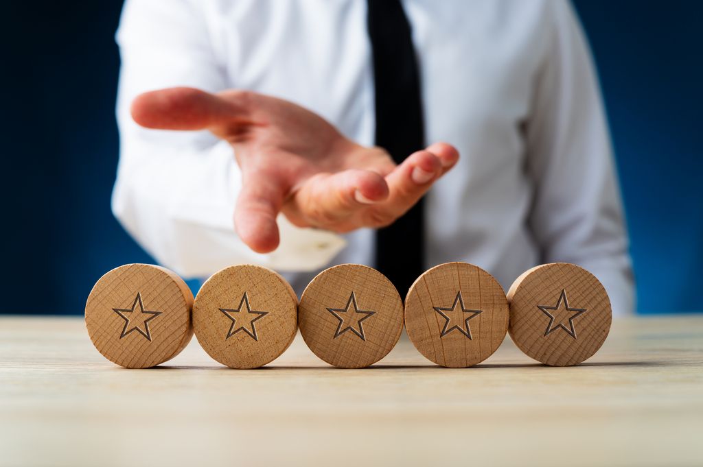 business man indicating 5 star rating with wooden blocks