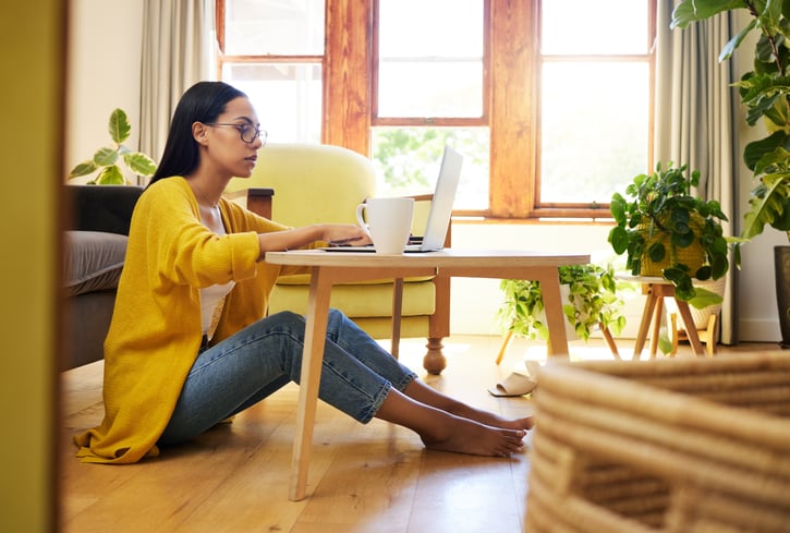 focused woman working remotely sitting on the floor in living room also know as mobile working