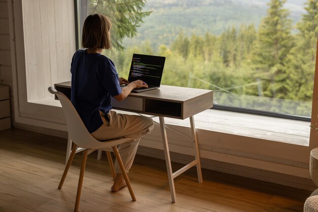 Vrouw werkt voor laptop voor het raam.