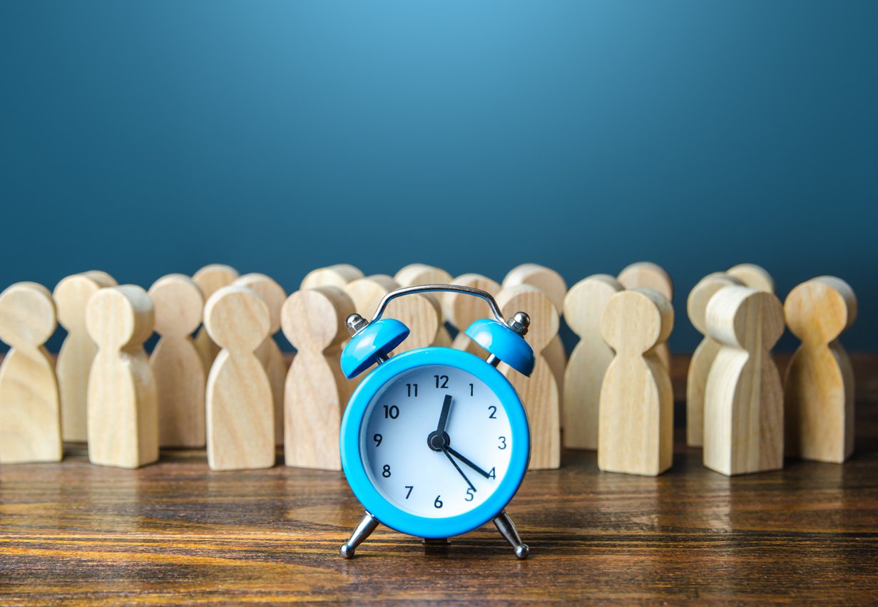 group of Human shaped wooden block with blue clock in front representing employee time tracking