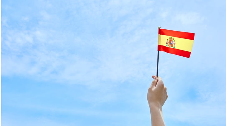 Mano sosteniendo la bandera española simbolizando las fiestas españolas.