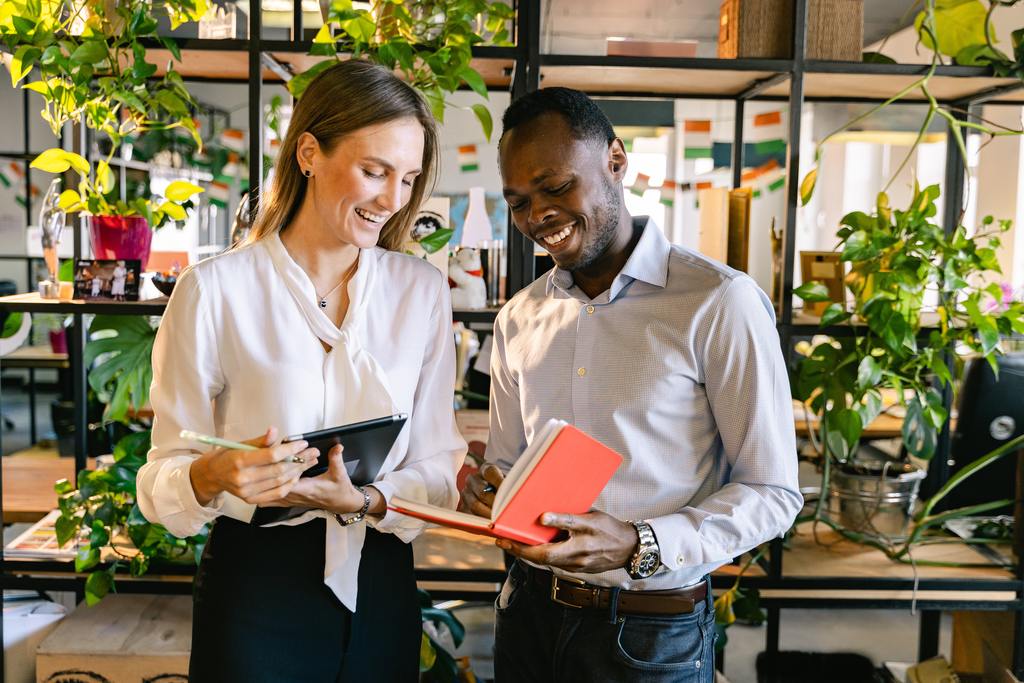 happy female and male employee looking on project notes in red notebook 