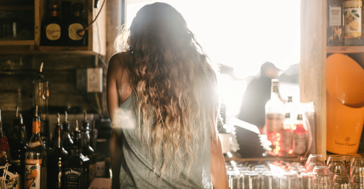 Achteraanzicht van een vrouw die achter een bar staat