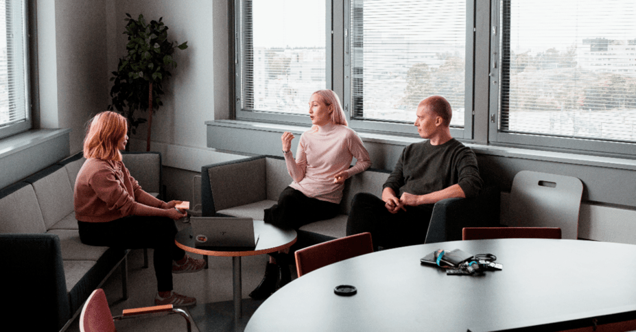 drie collega's zitten op stoelen en zijn in gesprek.