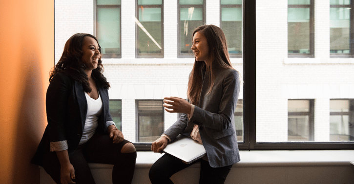 Twee vrouwen zitten in het vensterbank en hebben een gesprek 