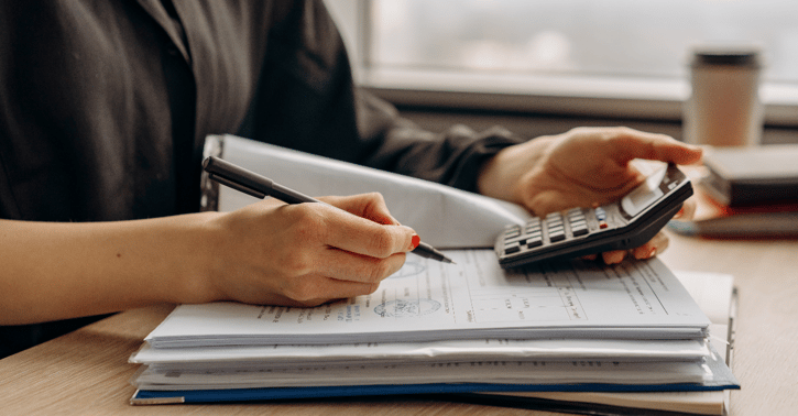 Vrouw bekijkt rekenmachine en schrijft resultaten op