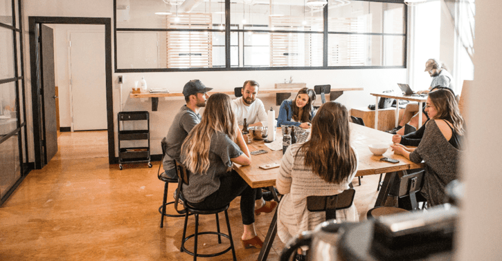 Collega's zitten aan een tafel en houden een vergadering