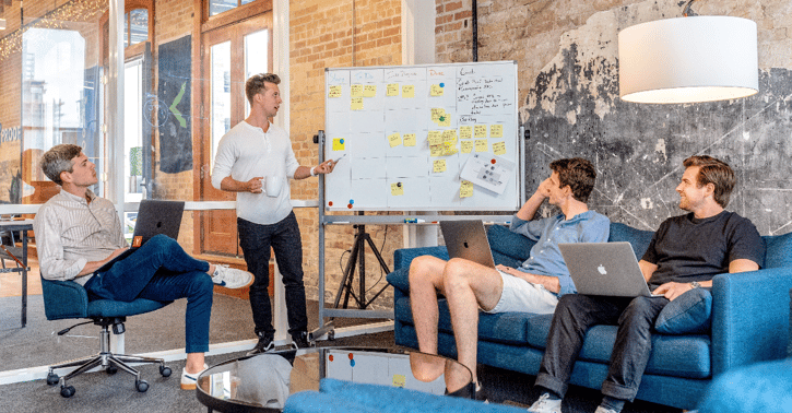 Team zit voor whiteboard en is in bespreking