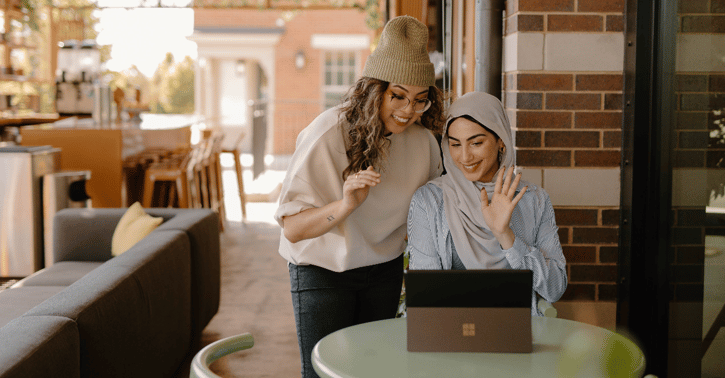 Twee vrouwen zwaaien naar de tablet die op tafel staat