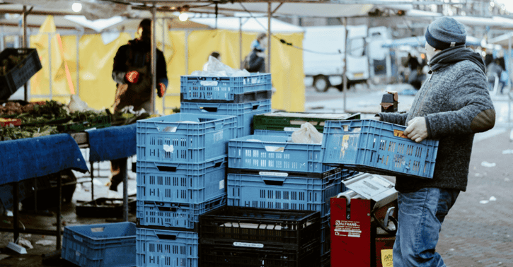 Man tilt kratten op de markt