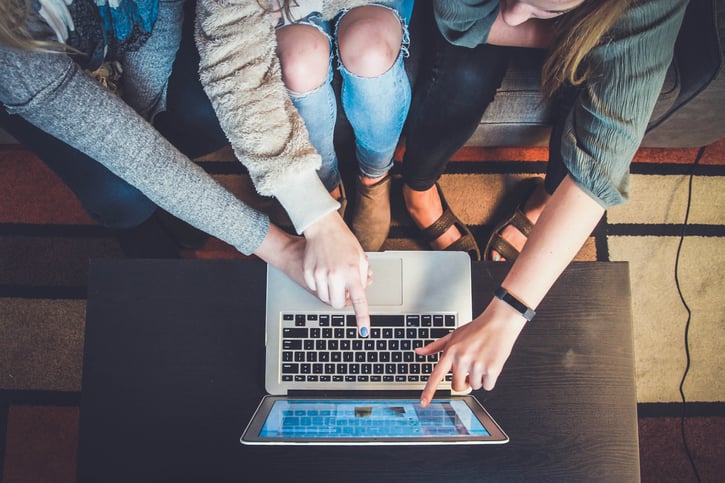 Meerdere mensen wijzen naar een laptop 