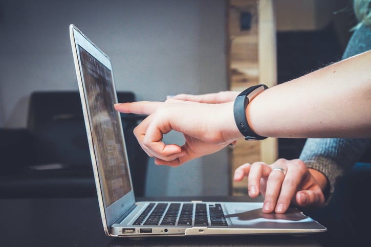 Hand wijst naar laptopscherm, zijaanzicht