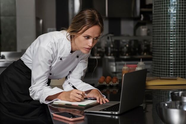 kitchen chef going over end of shift report on laptop