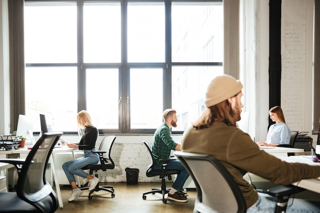 Mitarbeiter nutzen verschiedene Arbeitsplätze in einem Büro mit Hot-Desking-Konzept.
