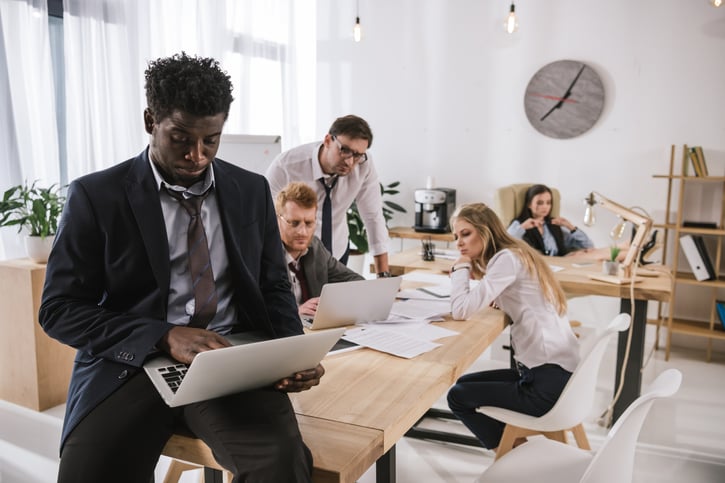 male employee working alone excluded from team symbolising favoritism at work