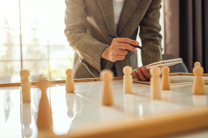 manager counting wooden blocks and making notes symbolising headcount reporting