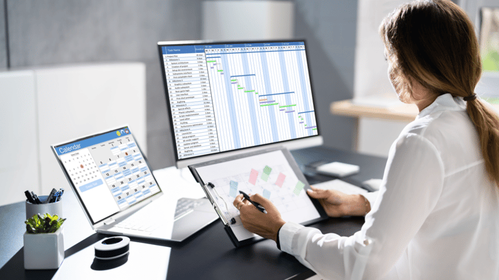 manager looking at employee schedules on laptops in an office setting