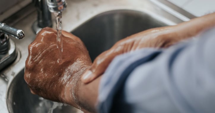 Man houdt verbrande hand onder koude kraan