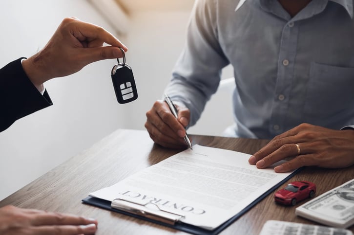 New car buyers sign contract documents for new company car symbolising salary sacrifice car scheme