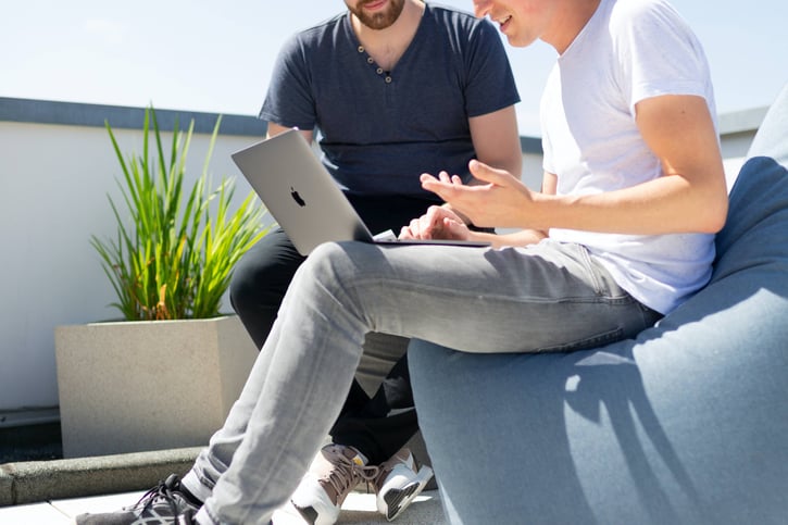 Mannen zitten voor een laptop en zijn in gesprek 