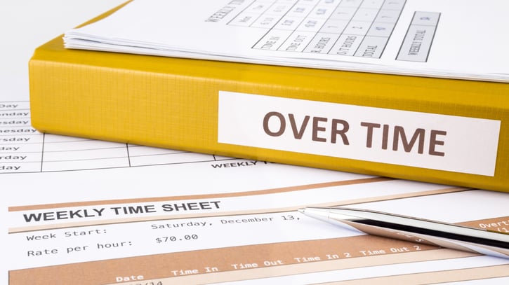 overtime written on yellow binder placed on weekly time sheets