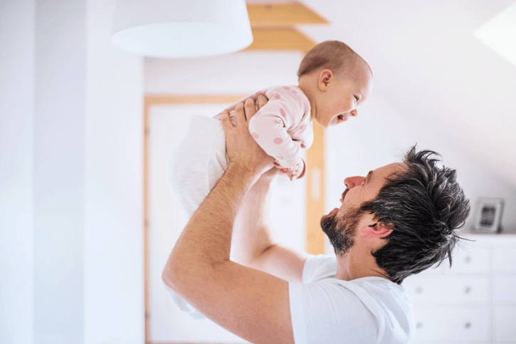 Padre feliz sosteniendo a su bebé recién nacido en el aire