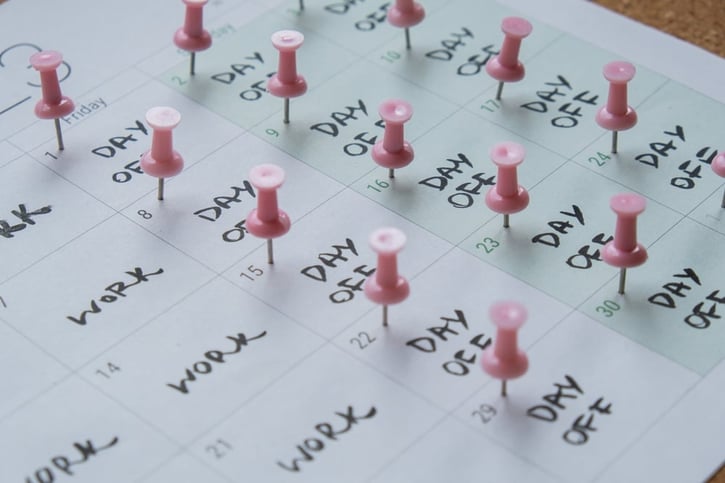 4 day work week schedule shown on a paper calendar with pinned emphasis on the days off 