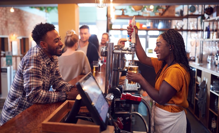smiling bartender serving beer to customer, bar hospitality