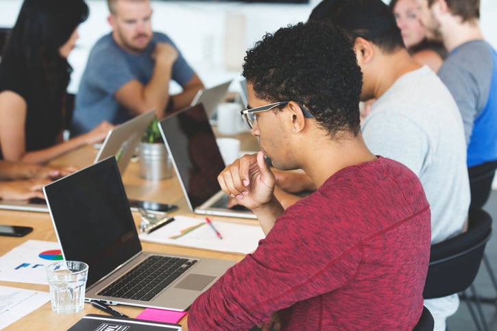 Persoon kijkt naar laptop die op tafel staat zij aanzicht
