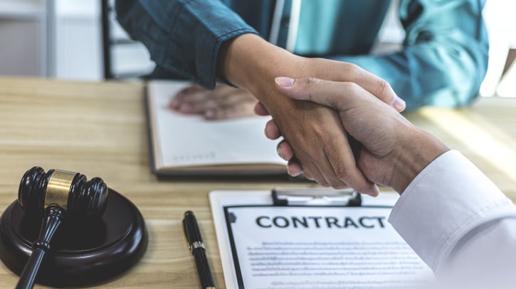 two people shaking hands over contract document on the table  symbolising a fixed term contract