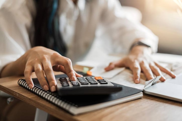 Mujer usando calculadora y nota para calcular ingresos o gastos