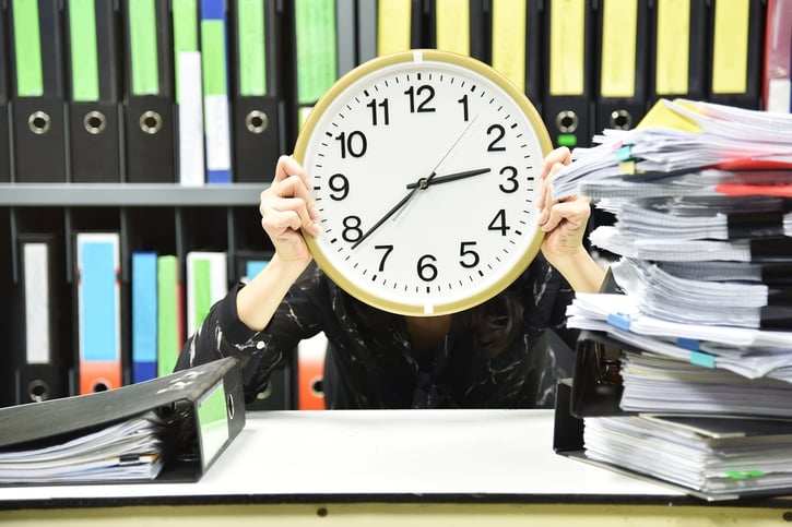 man holding large clock in front face symbolising overtime tracking