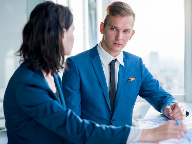 Bild eines Bürotreffens mit einem Arbeitnehmer und einem Personalverantwortlichen, die Arbeitsdokumente durchgehen, symbolisiert Weiterbeschäftigung und Weiterbeschäftigungsanspruch im Kontext des Arbeitsrechts. Der Anspruch des Mitarbeiters auf Fortsetzung seiner Tätigkeit wird diskutiert