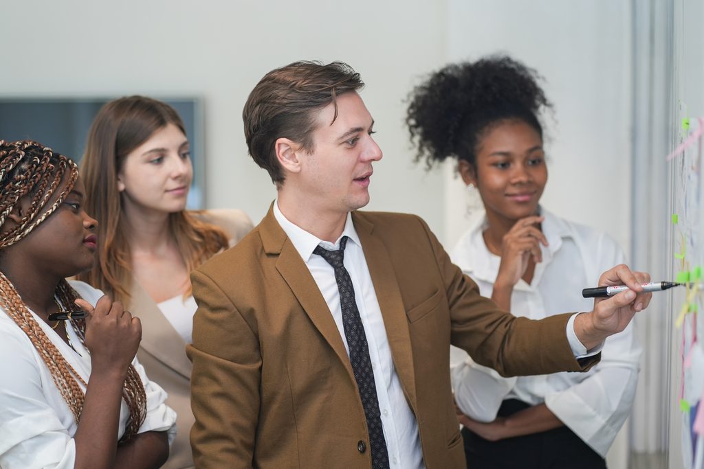 Diverse business people in a meeting room looking at white board