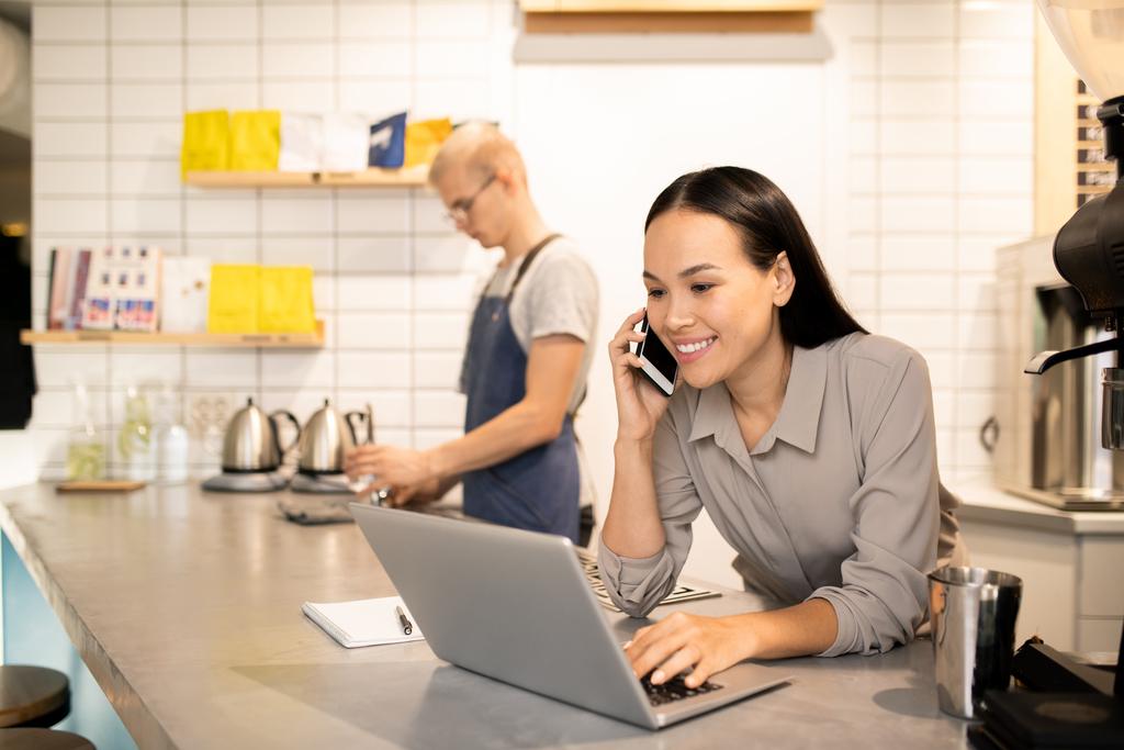 Restaurant manager working on laptop while talking on the phone